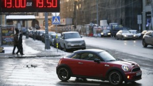 A car drives near an electronic board showing currency exchange rates in central Moscow