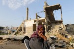 A Palestinian woman sits near her house, that witnesses said was destroyed by Israeli shelling during a 50-day war last summer, in Khan Younis in the southern Gaza Strip, March 10, 2015. A Qatari official visiting a Gaza neighbourhood heavily bombed in last summer's war with Israel said on Tuesday the Gulf Arab state had begun a project to rebuild 1,000 homes as part of a $1 billion aid pledge. REUTERS/Ibraheem Abu Mustafa (GAZA - Tags: POLITICS CIVIL UNREST SOCIETY TPX IMAGES OF THE DAY) - RTR4ST86