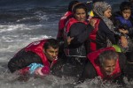 A group of Afghan migrants, including a small child carried through the water by man at left, disembark safely from their frail boat in bad weather on the Greek island of Lesbos after crossing the Aegean see from Turkey, Wednesday, Oct. 28, 2015. Greeces government says it is preparing a rent-assistance program to cope with a growing number of refugees, who face the oncoming winter and mounting resistance in Europe. (AP Photo/Santi Palacios)