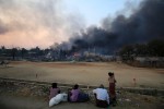 Smoke rises as people look on in Meikhtila, March 21, 2013. The central Myanmar town declared a curfew for a second night on Thursday after clashes killed 10 people, including a Buddhist monk, and injured at least 20, authorities said. Riots erupted in Meikhtila, 540 km (336 miles) north of Yangon, on Wednesday after an argument between a Buddhist couple and the Muslim owners of a gold shop escalated.  REUTERS/Soe Zeya Tun   (MYANMAR - Tags: CIVIL UNREST RELIGION) - RTR3F9XV