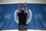 A worker sets up a United Nations banner at the media center in preparations for the start  of this week's Syria peace talks in Montreux and Geneva, in Montreux, Switzerland, Tuesday, Jan. 21, 2014. Russia and Iran on Tuesday criticized the U.N. chiefs decision to withdraw Tehrans invitation to join the peace conference on Syria, as diplomats said a new report on Syrian regime atrocities underscored the urgent need to try to end the countrys brutal civil war.   (AP Photo/Anja Niedringhaus)