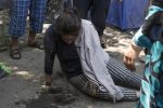 A woman sits on the ground after having a heat stroke at a migrant camp at Serbia's border with Hungary, in Horgos, Serbia, Wednesday, July 13, 2016. Hungarian police and soldiers have beaten some migrants severely before sending them back across the border to Serbia, Human Rights Watch said in a report released Wednesday. (AP Photo/Marko Drobnjakovic)