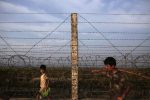 A Rohingya boy and a man walk along the fence separating Myanmar and Bangladesh as they return from a fish market in Maungdaw town in northern Rakhine State November 11, 2014.  REUTERS/Minzayar