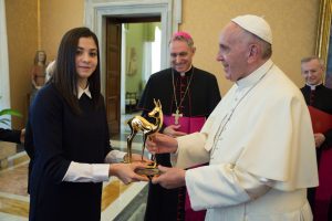 A handout picture taken on November 10, 2016 and released on November 11, 2016 by the Vatican press office Osservatore Romano shows Pope Francis receiving the "Bambi Award" from Syrian swimmer Yusra Mardini.  Mardini gained international attention after surviving near-drowning while crossing the Mediterranean Sea with fellow refugees. She now lives in Germany and competed in this year's Rio Olympics as part of a refugee team. More than 300,000 people have been killed and over half Syria's population displaced by the conflict since it began with anti-government demonstrations in March 2011. / AFP PHOTO / OSSERVATORE ROMANO / OSSERVATORE ROMANO