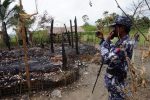 A Myanmar border guard police officer takes pictures at the remains of a burned house in Tin May village, northern Rakhine state, Myanmar July 13, 2017. Picture taken July 13, 2017.  REUTERS/Simon Lewis