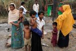 A family stands beside remains of a market which was set on fire, in Rohingya village outside Maungdaw, in Rakhine state, Myanmar October 27, 2016. Picture taken October 27, 2016.  REUTERS/Soe Zeya Tun