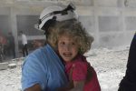 This photo provided by the Syrian Civil Defense group known as the White Helmets, shows a civil defense worker carrying a child after airstrikes hit a school housing a number of displaced people, in the western part of the southern Daraa province of Syria, Wednesday, June 14, 2017. A U.N. investigative commission said Wednesday that the "de-escalation" agreement in Syria has reduced violence in only one of four zones included in the deal and has not led to greater humanitarian access. (Syrian Civil Defense White Helmets via AP)