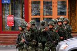 FILE PHOTO: Paramilitary policemen gesture to stop a photographer from taking pictures as they stand guard after an explosives attack hit downtown Urumqi in the Xinjiang Uighur Autonomous Region May 23, 2014.  REUTERS/Petar Kujundzic/File Photo