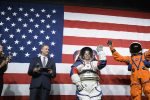 Amy Ross, a spacesuit engineer at NASAs Johnson Space Center, left, and NASA Administrator Jim Bridenstine, second from left, watch as Kristine Davis, a spacesuit engineer at NASAs Johnson Space Center, wearing a ground prototype of NASAs new Exploration Extravehicular Mobility Unit (xEMU), and Dustin Gohmert, Orion Crew Survival Systems Project Manager at NASAs Johnson Space Center, wearing the Orion Crew Survival System suit, right, wave after being introduced by the administrator, Tuesday, Oct. 15, 2019 at NASA Headquarters in Washington. The xEMU suit improves on the suits previous worn on the Moon during the Apollo era and those currently in use for spacewalks outside the International Space Station and will be worn by first woman and next man as they explore the Moon as part of the agencys Artemis program. The Orion suit is designed for a custom fit and incorporates safety technology and mobility features that will help protect astronauts on launch day, in emergency situations, high-risk parts of missions near the Moon, and during the high-speed return to Earth.  Photo Credit: (NASA/Joel Kowsky)