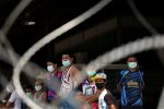 FILE PHOTO: Migrant workers stand in front of a closed shrimp market, amid the coronavirus disease (COVID-19) outbreak, in Samut Sakhon province, in Thailand, December 20, 2020. REUTERS/Athit Perawongmetha