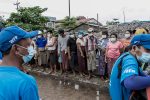 In this photo taken on May 21, 2021, people wait to receive bags of rice distributed by the World Food Programme (WFP) as part of food aid efforts to support residents living in poor communities on the outskirts of Yangon. - Myanmar's economy and banking system have been paralysed since the military's power-grab in early February, leading to disaster for millions of people who the World Food Programme has warned could go hungry in the coming months. (Photo by STR / AFP) / To go with MYANMAR-COUP-POLITICS-FOOD, FOCUS